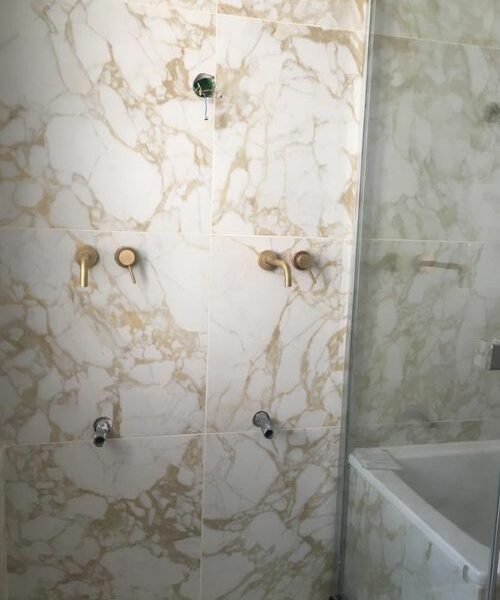 Mur de salle de bain avec faïence effet marbre et robinetterie dorée