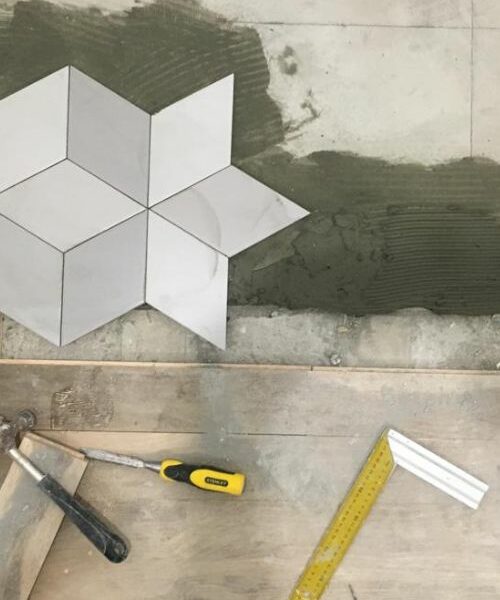Carrelage à motif géométrique en cours de pose avec outils