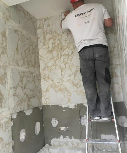 Artisan posant du carrelage marbré sur les murs d’une salle de bain