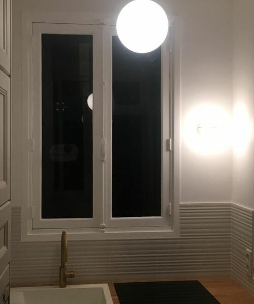 Évier avec robinet doré devant une fenêtre dans cuisine rénovée