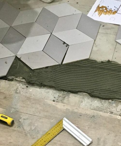 Pose de carrelage 3D sur chantier avec plan et outils au sol