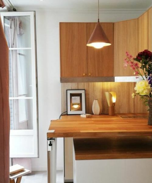Cuisine avec mobilier bois, suspensions cuivrées et décoration florale