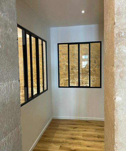 Verrière noire avec vue sur mur en pierre