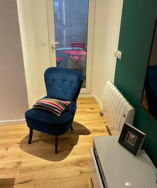 Fauteuil bleu dans salon rénové avec accès terrasse