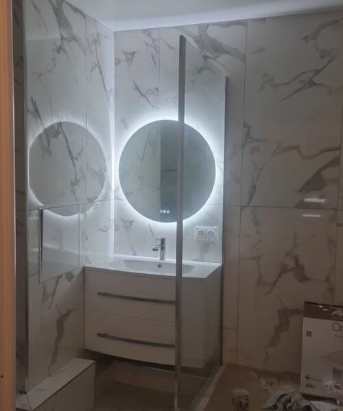 Salle de bain marbrée avec miroir LED circulaire