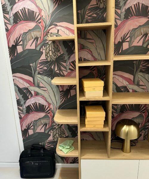 Étagères en bois devant un mur avec papier peint floral