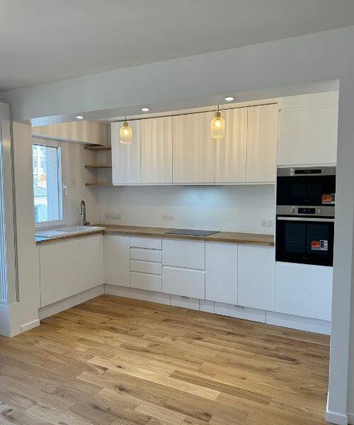 Cuisine blanche avec plan de travail bois clair et électroménager intégré