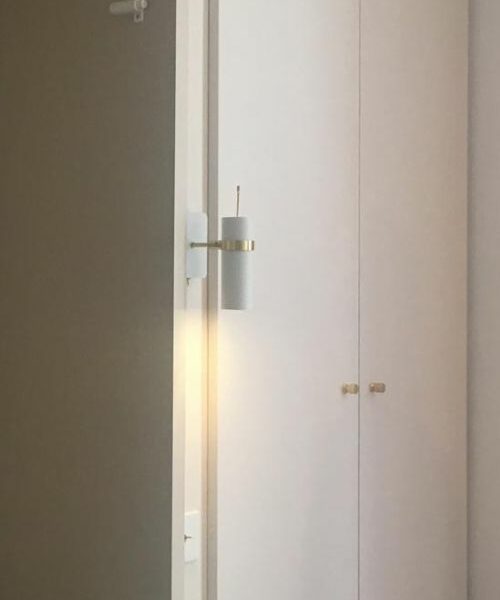 Applique blanche avec détails laiton sur cloison beige