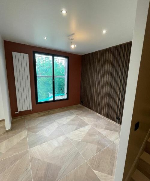 chambre rénovée avec mur en lames bois et peinture couleur terre cuite à Paris