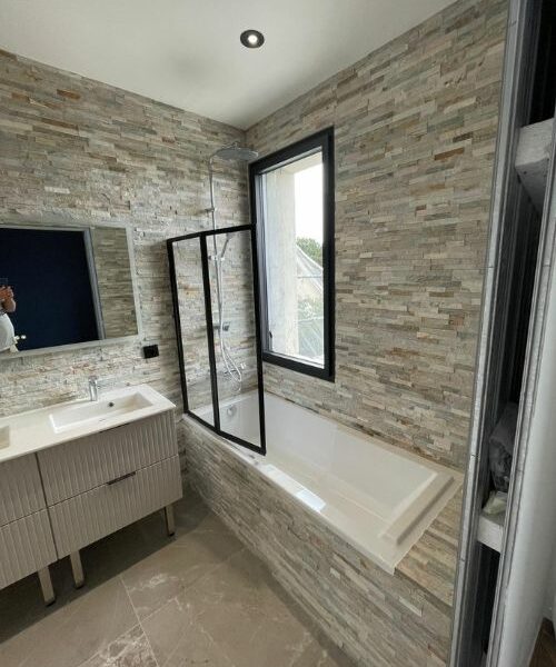 salle de bain lumineuse rénovée avec baignoire et double vasque à Paris