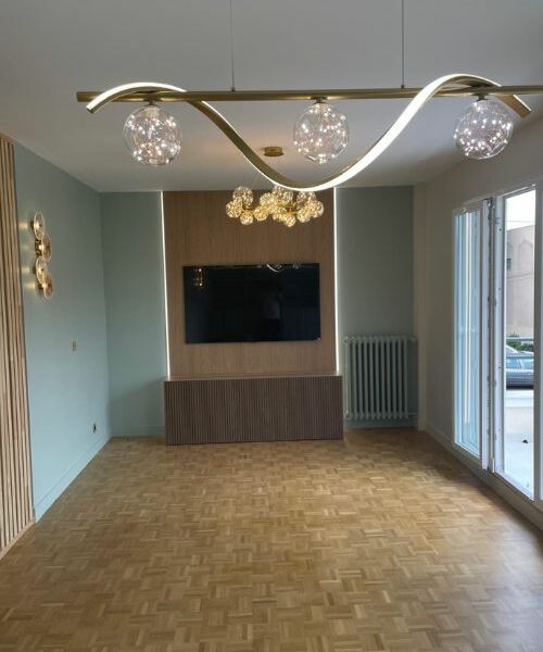 salon rénové avec éclairage doré et mur TV en bois clair à Paris
