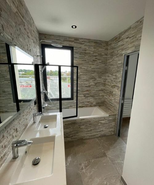 salle de bain rénovée avec baignoire et mur en pierre naturelle à Paris