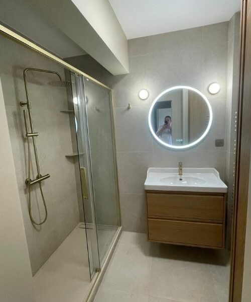 salle de bain moderne avec douche vitrée et robinetterie dorée à Paris