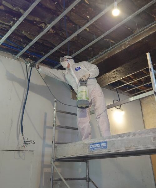 ouvrier traitant la charpente avant isolation à Paris