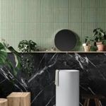 Salle de bain avec carrelage vert pastel et plan de toilette en marbre noir